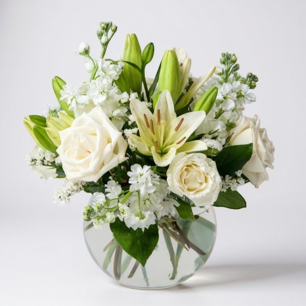 White rose and lily floral arrangement in a round glass vase