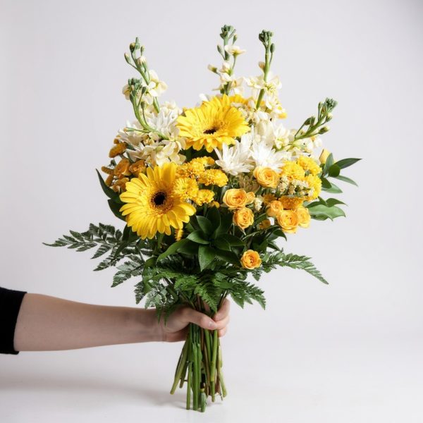 Yellow and white bouquet with gerbera daisies, roses, carnations, and lush greenery