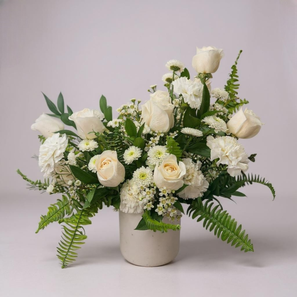 Elegant white rose and carnation flower arrangement in ceramic vase with greenery