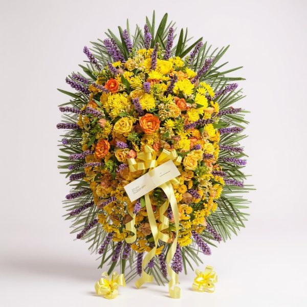 Funeral standing spray with yellow chrysanthemums, orange roses, purple accents, greenery, and yellow ribbon bow on easel
