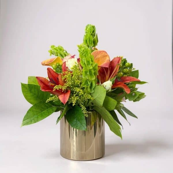 Golden Glow flower arrangement with red lilies, Bells of Ireland, and greenery in a metallic gold vase