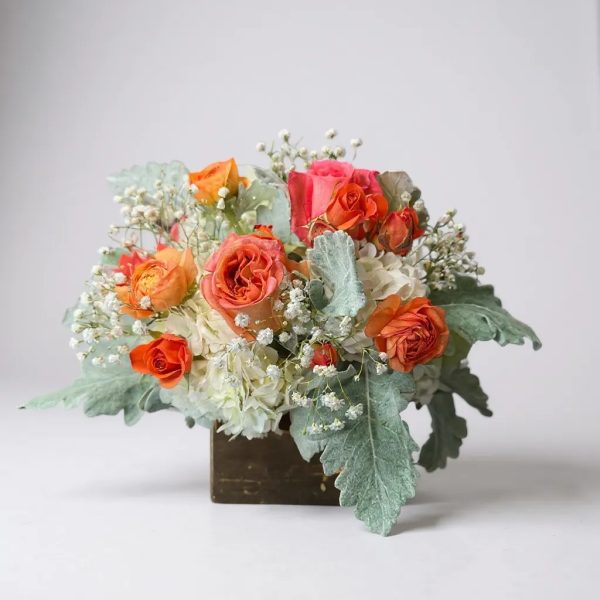 vase arrangement with orange roses, hydrangeas, and dusty miller