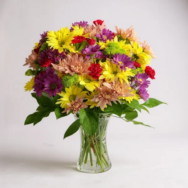 Bright and cheerful flower arrangement with yellow daisies, red carnations, purple mums, and peach-toned chrysanthemums in a clear glass vase