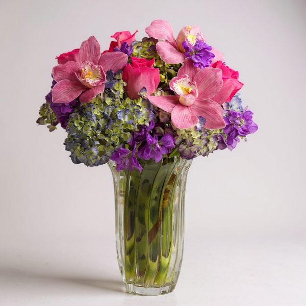 orchid reverie flower arrangement with pink orchids, roses, and hydrangeas in chanterelle ribbed vase