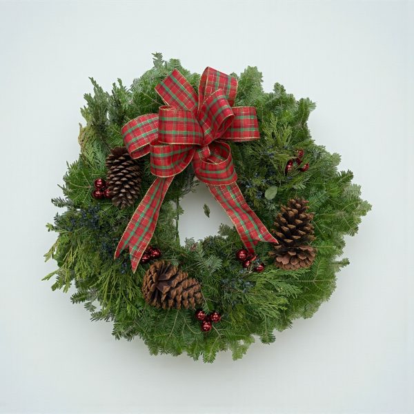 Christmas wreath with pinecones, red berries, and plaid bow on fresh evergreens
