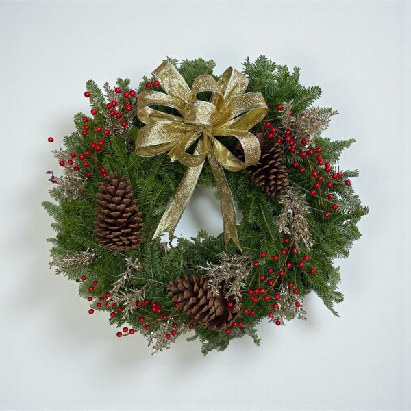 Christmas wreath with gold bow, gold foliage, red berries, pinecones, and fresh evergreen branches.