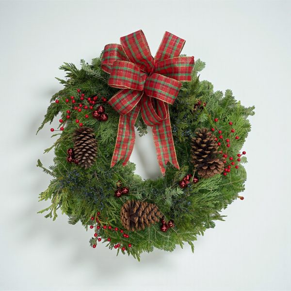 Christmas wreath with tartan bow, red berries, pinecones, and fresh evergreen branches.