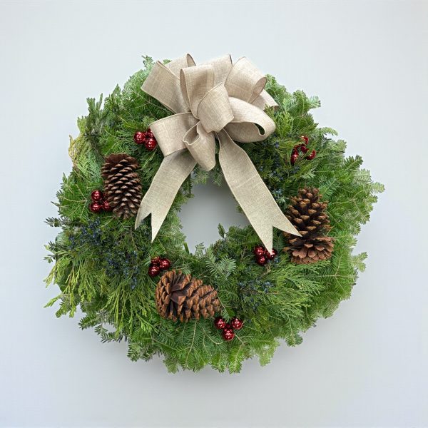 Christmas wreath with linen bow, red berries, pinecones, and fresh evergreen foliage