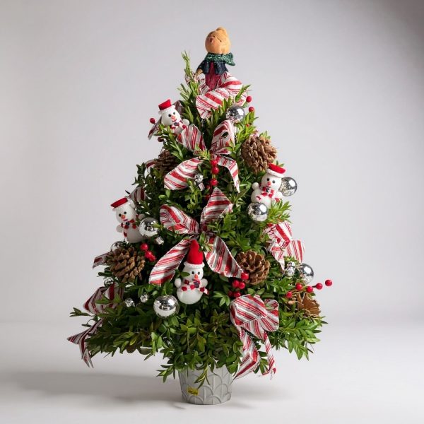 Whimsical decorated boxwood Christmas tree with candy cane ribbon, snowmen, and pinecones
