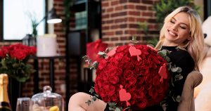 Woman holding large bouquet of best flowers for Valentine's Day featuring premium red roses with heart decorations