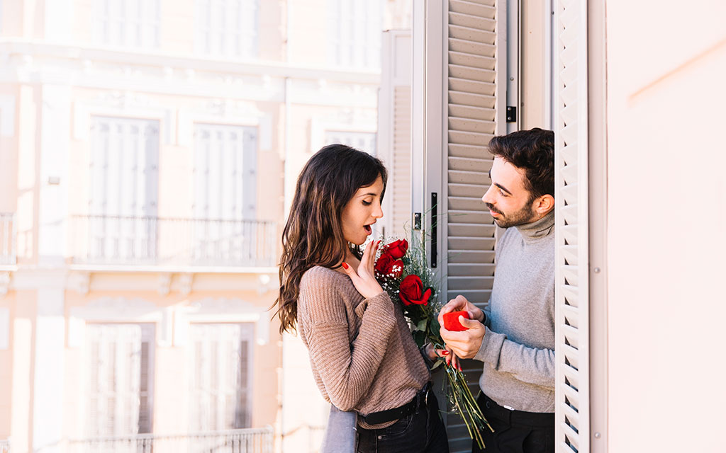 Man surprising partner with Valentine's Day roses delivery and gift, showing romantic gesture