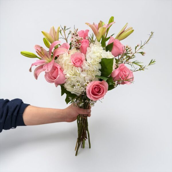 Pink lily bouquet with pink roses, white hydrangeas, waxflower, and fresh greenery hand-tied by Quinn Florist