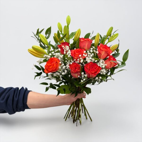 Coral rose bouquet with lily buds, baby’s breath, and fresh greenery hand-tied by Quinn Florist