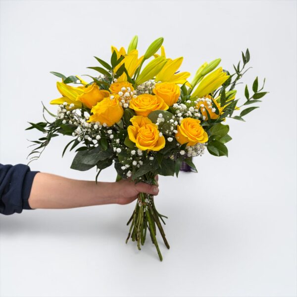 Yellow lily bouquet with yellow roses, baby’s breath, and fresh greenery hand-tied by Quinn Florist