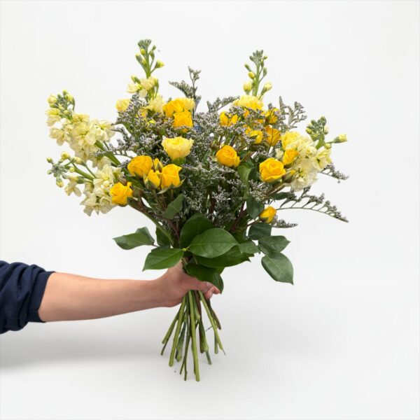 Yellow rose bouquet with white stock, delicate filler flower, and fresh greenery hand-tied by Quinn Florist