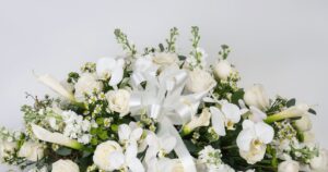 White casket spray of roses, orchids, calla lilies and stock, made by Quinn Florist in Astoria, New York