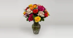 Quinn Florist mixed roses in pink, yellow, orange, red and blush in a clear glass vase